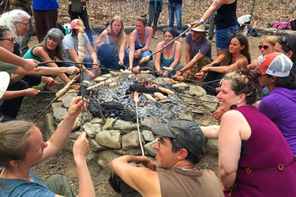 Roasting marshmellows around a campfire at Earthaven Ecovillage